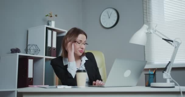 Tired Woman in Glasses Sitting at the Laptop while Working in the Office, then Almost Falling Asleep and Waking Up - Materiał filmowy, wideo