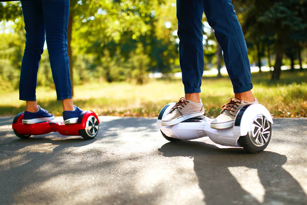 Legs of man and woman riding on the Hoverboard for relaxing time together outdoor at the city. A young couple riding a hoverboard in a park, self-balancing scooter. Active lifestyle technology future. - Fotó, kép