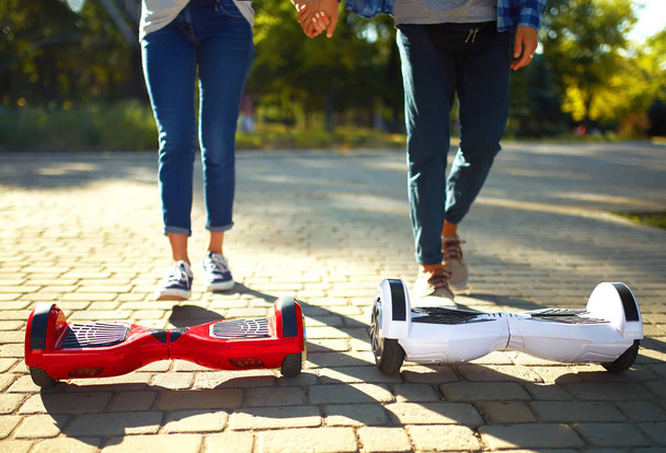 Legs of man and woman riding on the Hoverboard for relaxing time together outdoor at the city. A young couple riding a hoverboard in a park, self-balancing scooter. Active lifestyle technology future. - Fotoğraf, Görsel