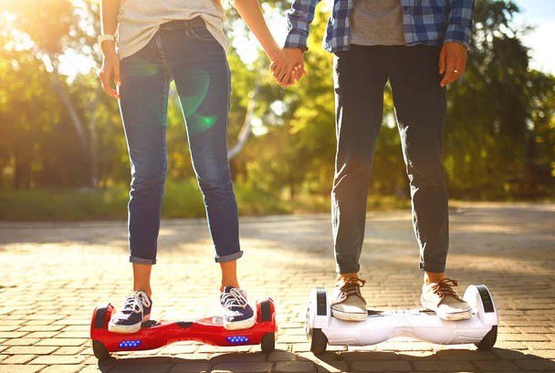 Legs of man and woman riding on the Hoverboard for relaxing time together outdoor at the city. A young couple riding a hoverboard in a park, self-balancing scooter. Active lifestyle technology future. - Fotó, kép