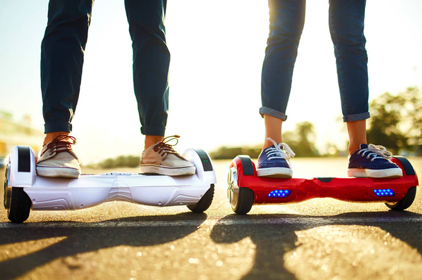 Legs of man and woman riding on the Hoverboard for relaxing time together outdoor at the city. A young couple riding a hoverboard in a park, self-balancing scooter. Active lifestyle technology future. - 写真・画像