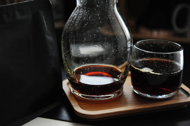Stílusos felszolgált speciális alternatív fekete kávé. Bambusztálca, kanna és üveg. Fekete csomag szabad hellyel a logóhoz. - Fotó, kép
