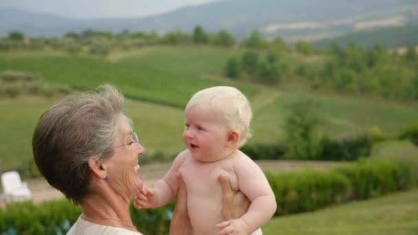 Średnie ujęcie babci wyrzucającej swojego uroczego wnuka w powietrze - Materiał filmowy, wideo