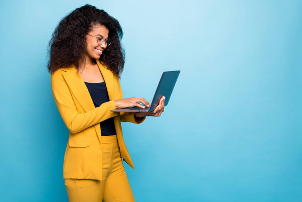 Profile photo of pretty assistant dark skin wavy lady holding notebook searching information internet help boss wear specs yellow suit blazer pants isolated blue color background - 写真・画像