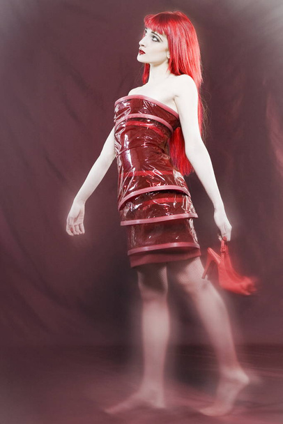 Funny & sexy expressive redhead girl wearing a palstic coat and dress on isolated backgroun - Foto, Imagem