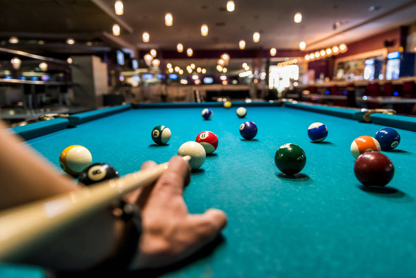 Hand with cue aiming on billiard ball at table - Φωτογραφία, εικόνα