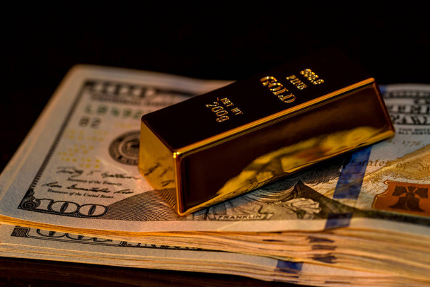 Złote sztabki na banknotach dolarowych z ciemnym tłem - Zdjęcie, obraz
