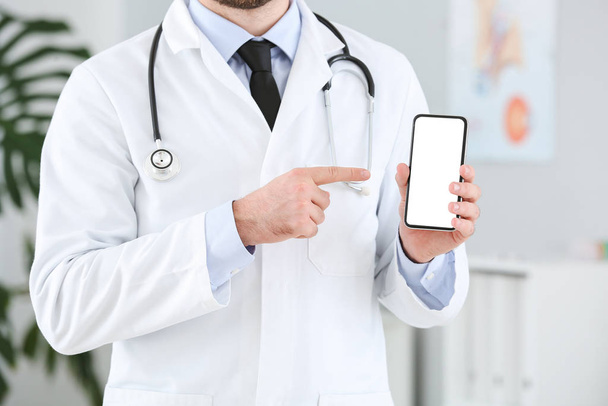 Médico masculino con teléfono móvil en la clínica
 - Foto, imagen