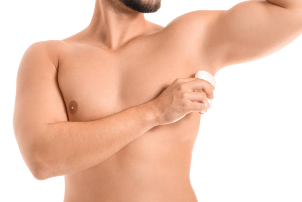 Handsome young man using deodorant on white background - Photo, image