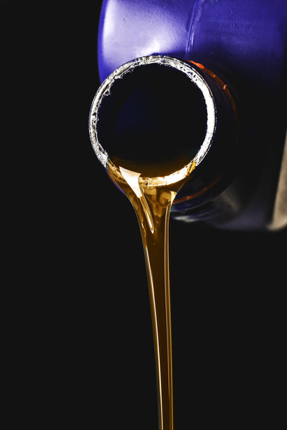 Can with pouring car oil on dark background - 写真・画像