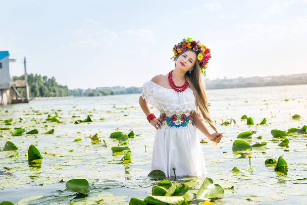Beautiful girl in national clothes standing in lake - Photo, Image