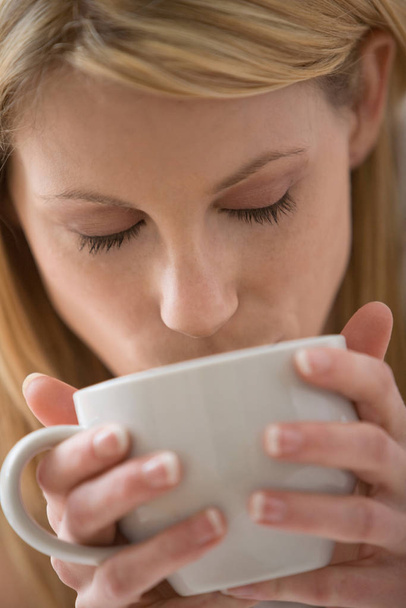 Close up of woman sipping from a white cup - Photo, Image