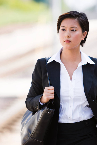 Business woman walking outside holding a black bag - Fotó, kép
