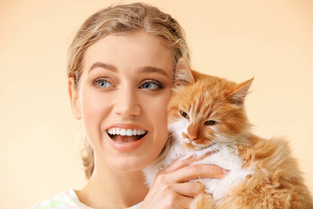 Beautiful young woman with cute cat on color background - Фото, зображення