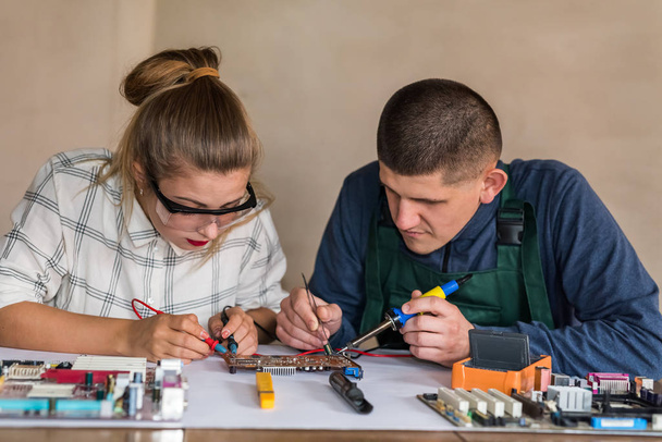 Man and woman repairing computer motherboard in workshop - Foto, Imagem