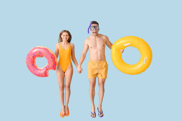 Jumping young couple with inflatable rings on color background - Fotografie, Obrázek