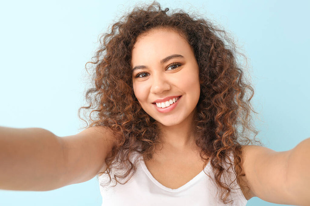 mooie jonge vrouw het nemen van selfie op kleur achtergrond - Foto, afbeelding
