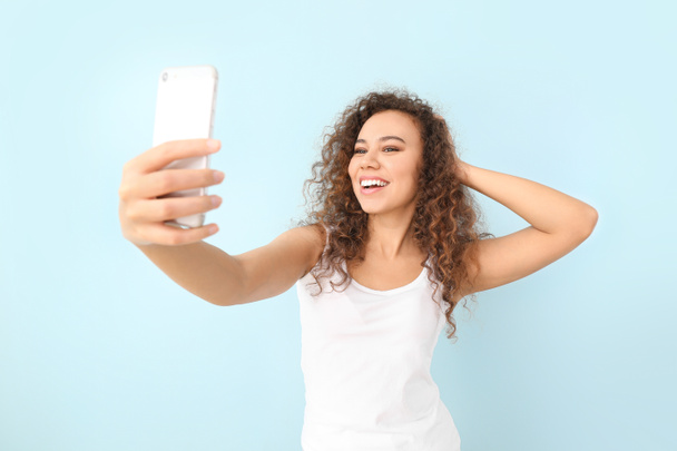 Beautiful young woman taking selfie on color background - Fotografie, Obrázek
