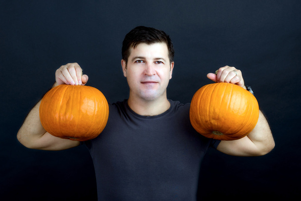adam siyah arka plan üzerine izole halloween pumpkins gösterir - Fotoğraf, Görsel