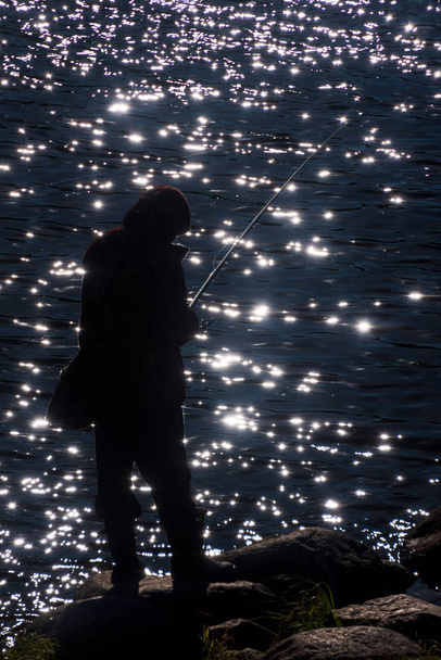 Fisherman Σιλουέτα ενάντια στον ήλιο που αντανακλά στο νερό - Φωτογραφία, εικόνα