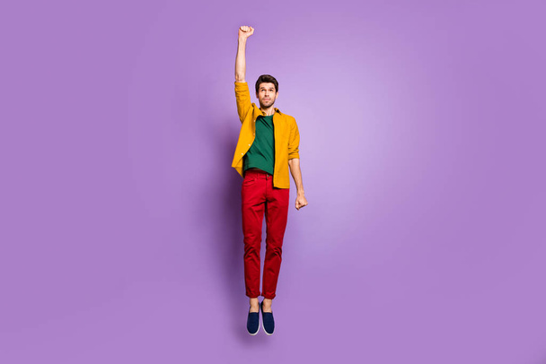 Super hero flight concept. Full body photo of focused playful guy jump relax raise fists up wear casual style clothing isolated over purple color background - Zdjęcie, obraz