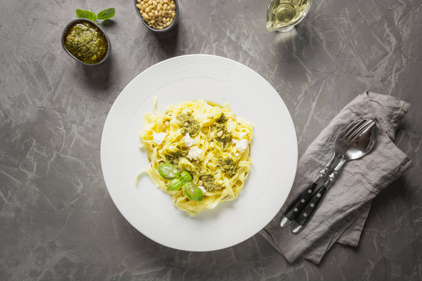 Pasta tagliatelle with pesto, pine nuts, cream cheese on grey background. Delicious Mediterranean lunch. - Foto, imagen