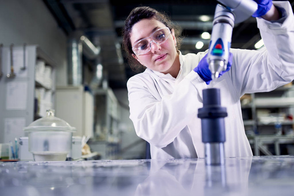 Woman lab technician in blue rubber gloves with 3D printer on defocused background - Foto, imagen