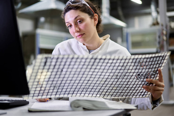 Gros plan femme technicienne de laboratoire assise à table avec un filet de carbone
 - Photo, image