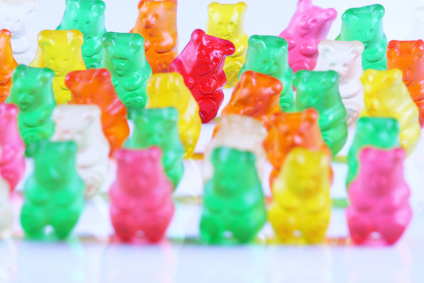 Colorful gummy bears lined up in rows, with the sole red bear being main focus. Isolated on white. - Foto, afbeelding