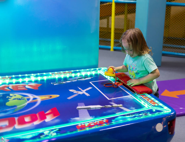 Lapsi pelaa ilmakiekkoa viihdekeskuksessa
 - Valokuva, kuva