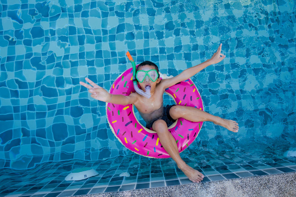 Zicht op jongen met zwemring drijvend in het zwembad - Foto, afbeelding