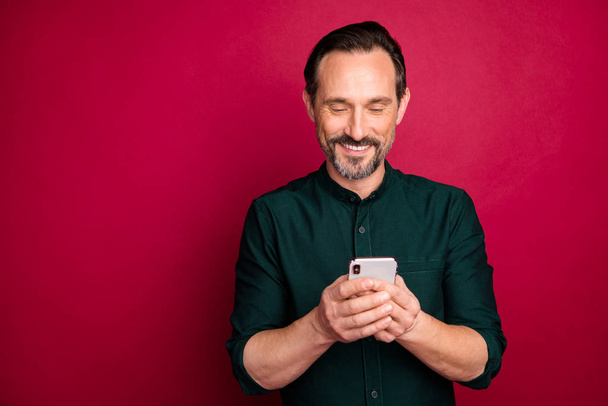 Close-up portrait of his he nice attractive cheerful cheery brown-haired man using digital gadget device isolated on bright vivid shine vibrant maroon burgundy marsala red color background - Foto, Bild