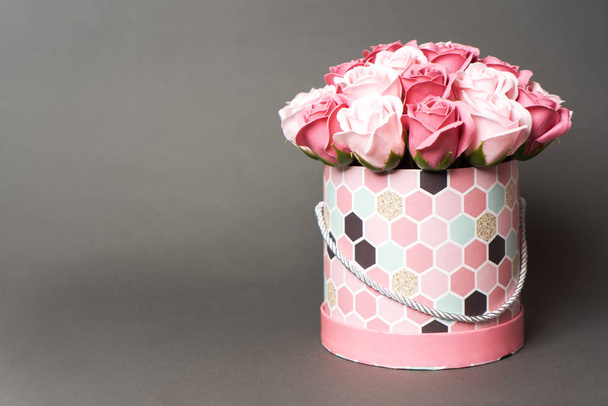 Flowers in bloom: A bouquet of pink and white roses in a round box on a gray background. - Fotó, kép