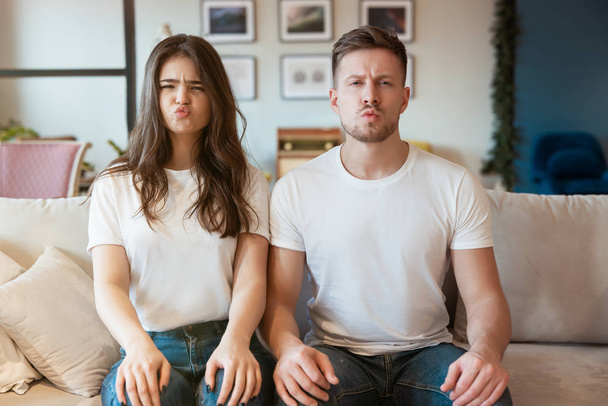 young couple man and woman sitting on the sofa looking upset, grimacing mood - Fotoğraf, Görsel