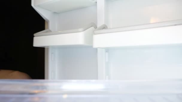 slanke hongerige man opent koelkast op zoek naar voedsel closeup - Video
