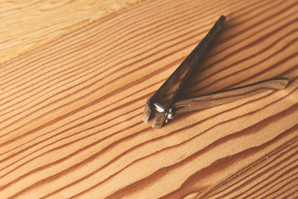 A closeup shot of a nail clipper on a wooden surface - Photo, image