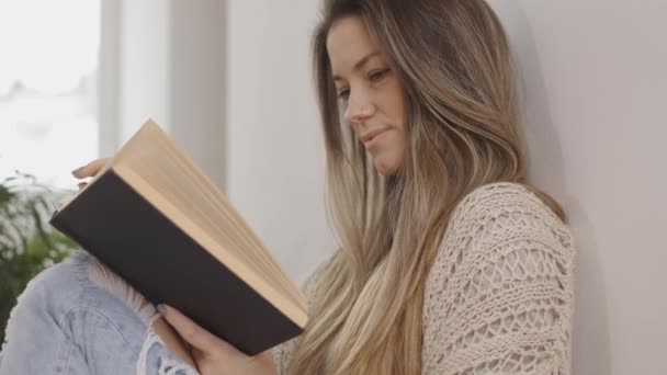 schöne junge Frau beim Lesen eines Buches, an die Wand gelehnt. 4k Zeitlupe, Handheld - Filmmaterial, Video