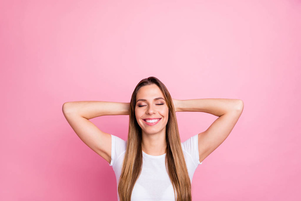 Photo of beautiful lady peaceful harmonic mood holding arms behind head eyes closed toothy dreamy smiling wear casual white t-shirt isolated pink color background - Foto, imagen