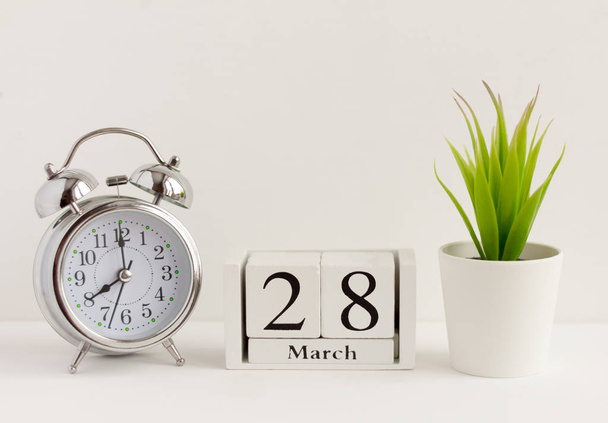 March 28 on a wooden calendar next to the alarm clock.Calendar date, holiday event, or birthday - Foto, Bild