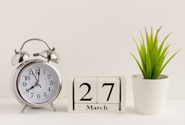 March 27 on a wooden calendar next to the alarm clock.Calendar date, holiday event, or birthday - Foto, Bild