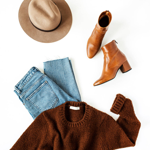 Flat lay fashion collage with women modern clothes and accessories on white background. Brown woolen pullover, shoes, hat, jeans. Lifestyle, beauty concept for blog, social media, magazine. - 写真・画像