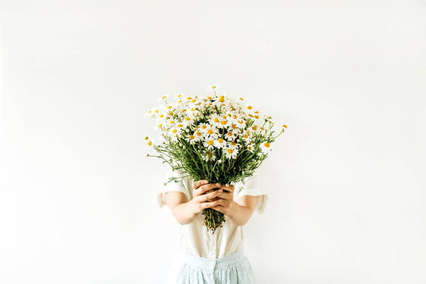 Jovem mulher bonita segurar em mãos buquê de flores margarida camomila branca no fundo branco
. - Foto, Imagem