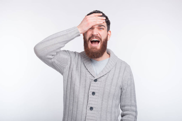 Face palm gesture is made by a young bearded man on white backgr - Фото, изображение
