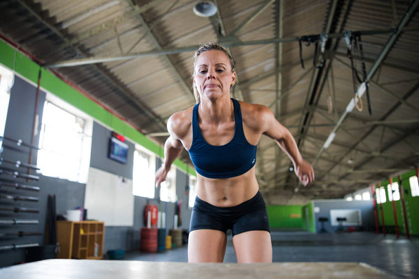 Female fitness athlete doing box jumps in a cross fit gym - Photo, Image