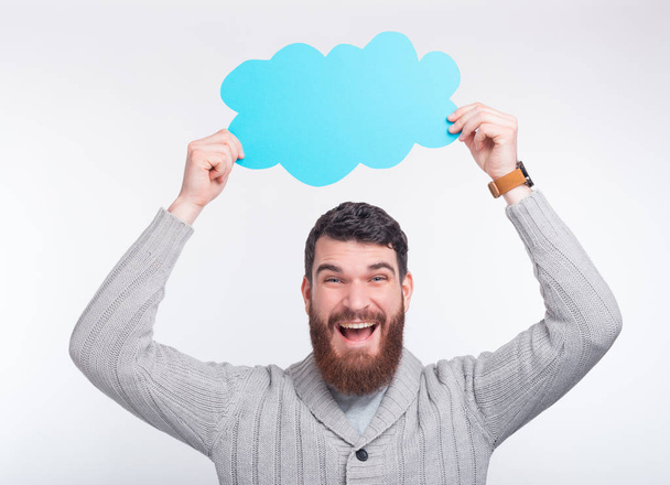Young bearded man is holding a blue cloud. Save files on digital - Fotoğraf, Görsel
