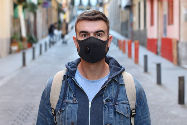 κοντινό πορτραίτο ενός όμορφου νεαρού άνδρα με προστατευτική μάσκα στο δρόμο - Φωτογραφία, εικόνα