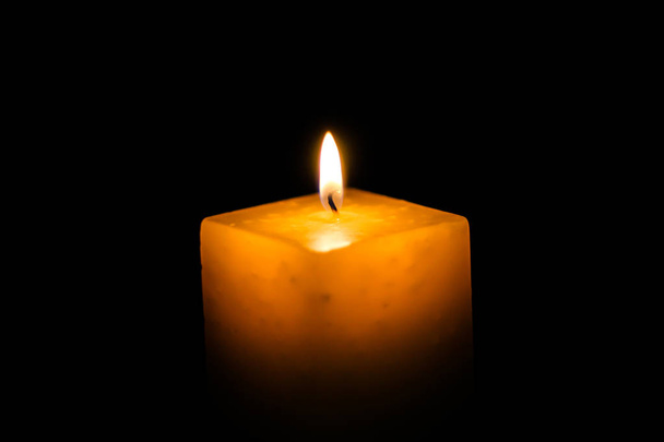 eine brennende Kerze auf einem neutralen schwarzen Hintergrund, ideal für die Textanwendung - Foto, Bild