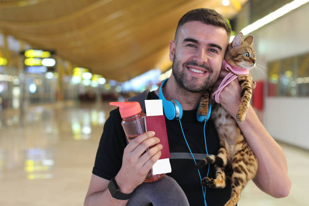 portrait de près d'un beau jeune homme voyageant avec son chat et se tenant debout dans le terminal de la gare - Photo, image