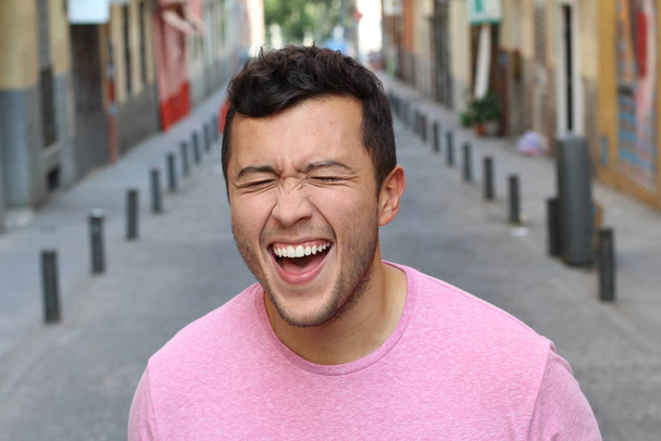 Молодой самец очень сильно смеется на улице - Фото, изображение