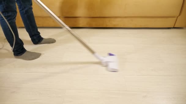 Felismerhetetlen ember porszívózik a padlón egy vezetékes porszívóval.. - Felvétel, videó
